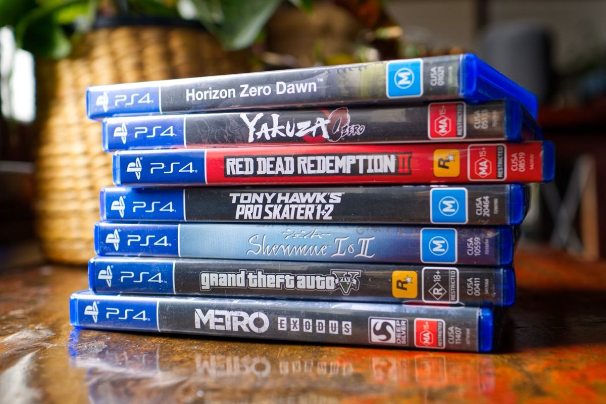 Stack of Ps4 Game Cases on a Wooden Table Showing Horizon Zero Dawn Yakuza Kiwamizero Red Dead Redemption Ii Tony Hawk's Pro Skater 1+2 Shenmue I & Ii Grand Theft Auto V and Metro Exodus
